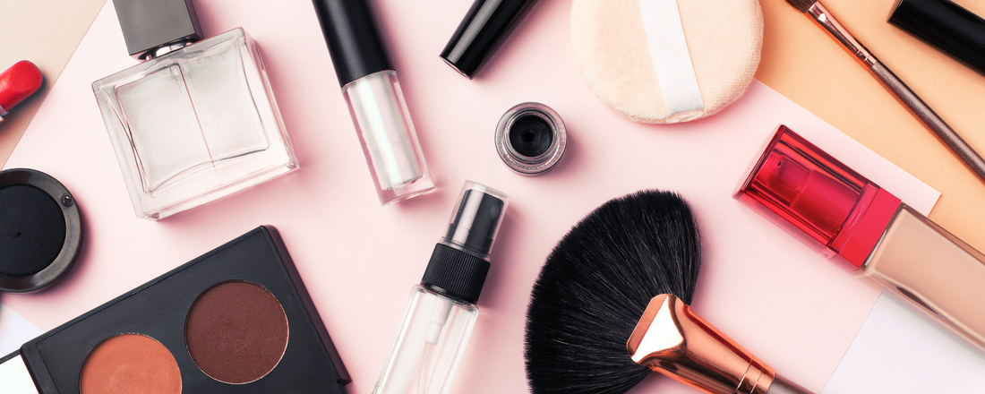 Various makeup products sitting on a pink background